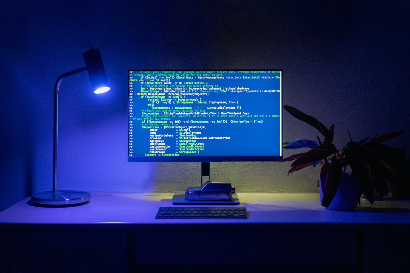 Computer monitor displaying code on a desk with a lamp.